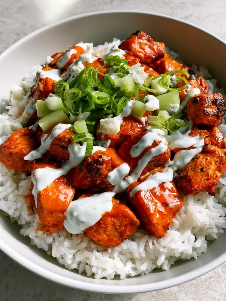 Close-up of air-fried chicken chunks in buffalo chicken bowls with diced celery and blue cheese garnishes.