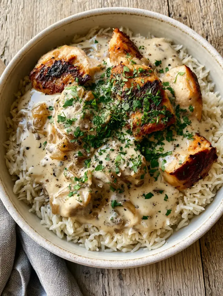 Smothered Chicken and Rice with Velvety Onion Gravy 1 Close up of long-grain rice topped with smothered chicken, caramelized onions, and cracked black pepper.