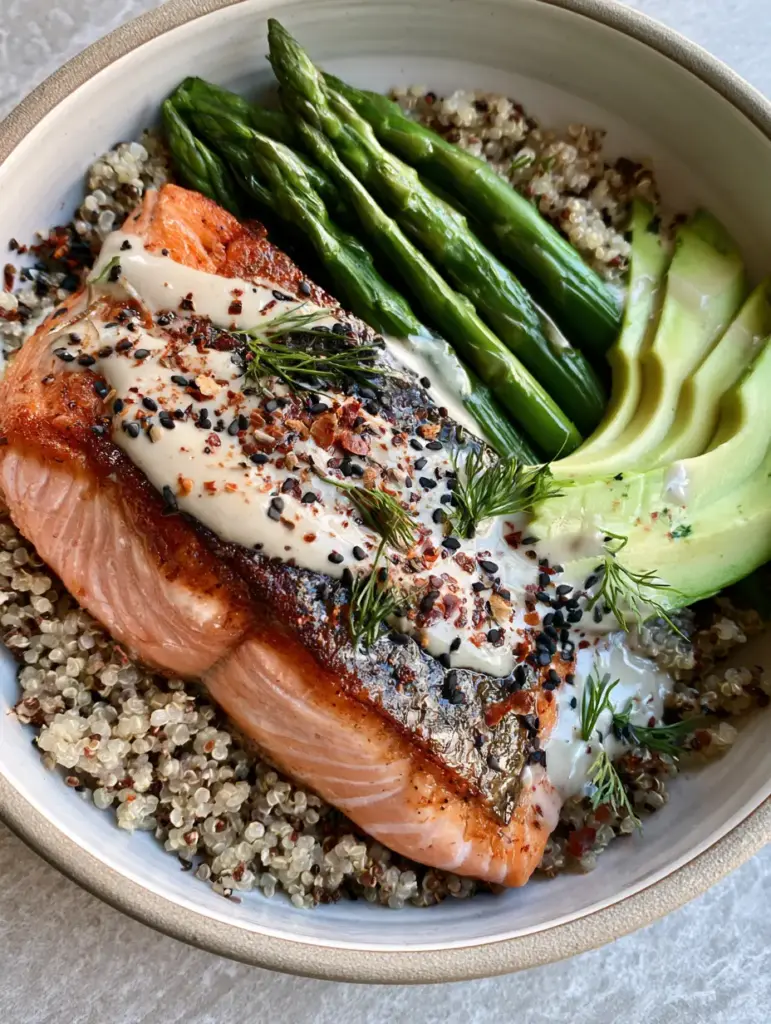 Recipe Ideas: Crispy Skin Seared Salmon and Toasted Quinoa Bowls 2 A top-down view of a ceramic bowl featuring seared salmon with golden skin on a bed of toasted quinoa. (Recipe Ideas)