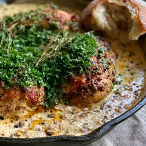 Close-up of seared Chicken au poivre showing the texture of the peppercorns and creamy bubbles in the sauce.