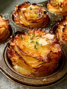 Smartphone photo of golden-brown potato stacks with glistening garlic butter and fresh thyme.