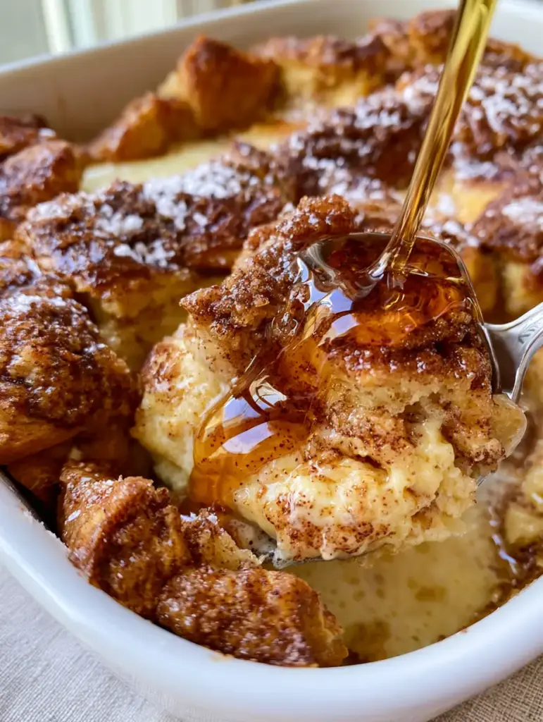 Overnight French Toast Casserole with Buttery Brioche and Cinnamon Streusel 1 Thick amber maple syrup being drizzled over a portion of brioche overnight French toast casserole.