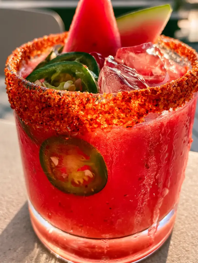 Jalapeño Watermelon Margarita: The Ultimate Spicy Summer Cocktail 1 Side view of a Jalapeño watermelon margarita glass with condensation droplets and a fresh watermelon wedge garnish.